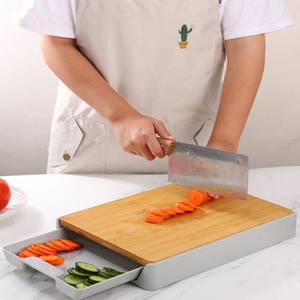 Person using a knife on a bamboo cutting board with vegetables on a kitchen counter