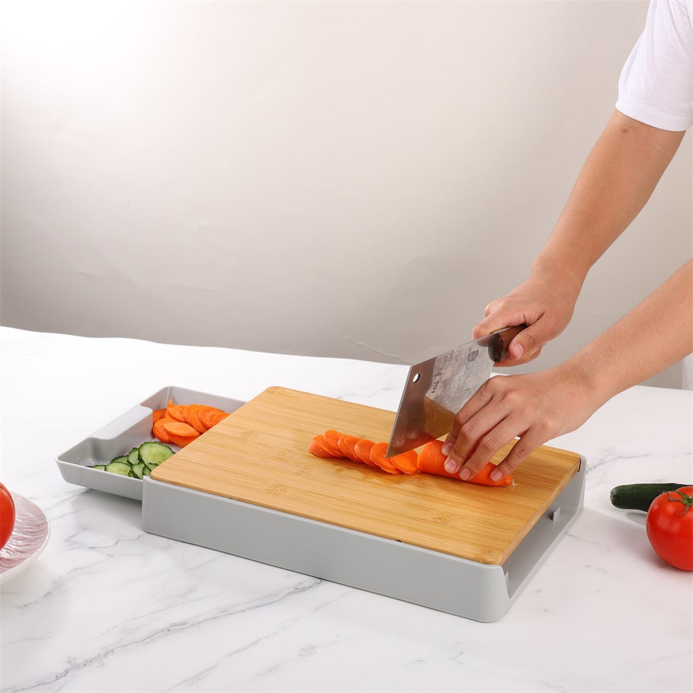 Person cutting vegetables on a bamboo cutting board with a gray tray underneath.