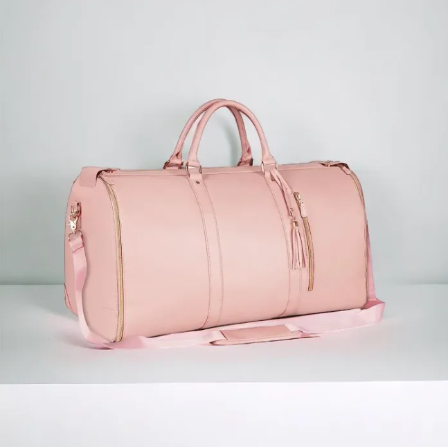 Pink duffel bag with gold zippers on a light gray background