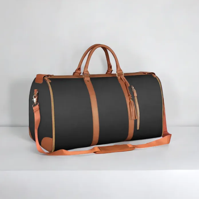 Black duffel bag with brown leather accents on a light gray background